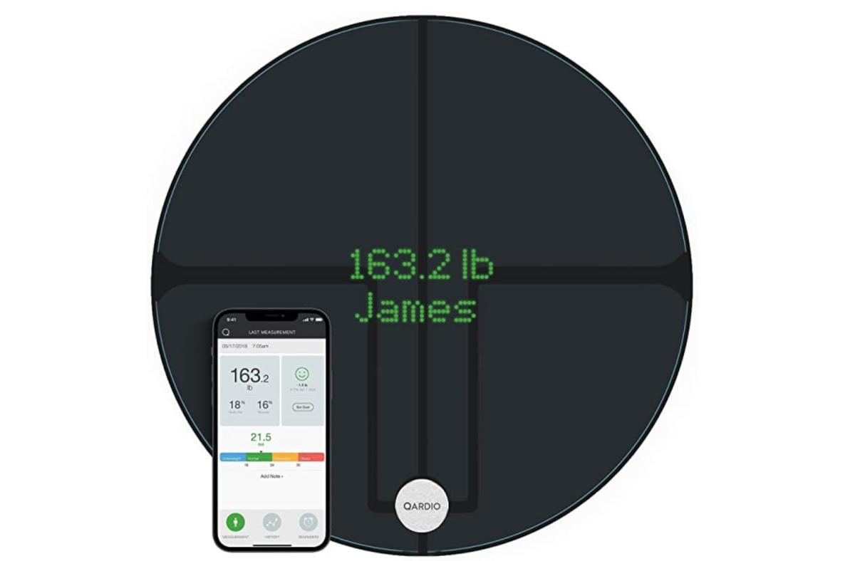 The circular Qardio Base 2 bathroom scale next to a smartphone opened to the Qardio app